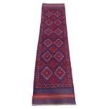 An Eastern wool runner principally in a red and blue colour way, with twin medallion panels. 241cm x