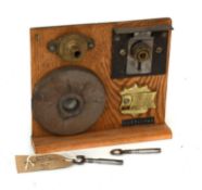 An 1851 Cotterill Climax Detector Lock, with two keys, mounted on an oak display board