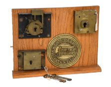 A Tucker & Reeves Powder Proof Safe Lock, number 37974, mounted on an oak stand with cast brass name