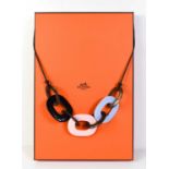 A Hermes buffalo horn Caramba necklace in pink and blue, on leather strap with original Hermes box.