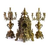 A brass garniture consisting of a Rococo style mantle clock with a Roman numeral dial and