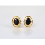 A pair of sapphire and diamond stud earrings, each designed as a central oval, untested sapphire