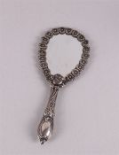 Een handspiegel in zilveren montuur met reliëf floraal decor, 20e eeuw, l 21,5 cm.