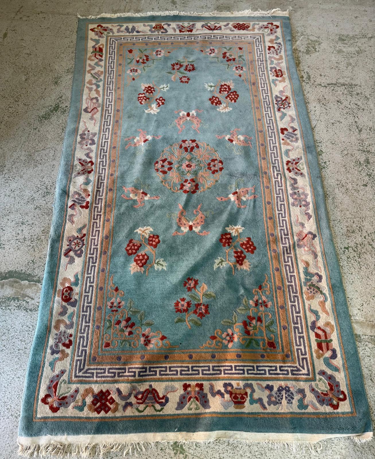 A wool rug, blue grounds with a floral border and central pattern (220cm x 124cm)