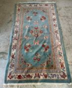 A wool rug, blue grounds with a floral border and central pattern (220cm x 124cm)