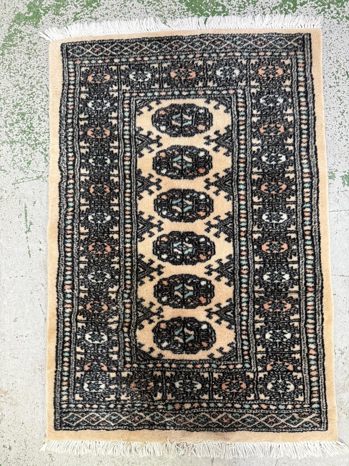 A wool rug. Beige grounds with geometric border.65x100cm