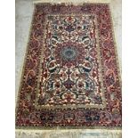 An Indian wool rug with beige grounds, with geometric border and a central shield (129cm x 189cm)