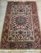 An Indian wool rug with beige grounds, with geometric border and a central shield (129cm x 189cm)