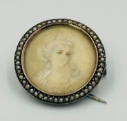 A miniature brooch with seed pearl surround and set in white metal