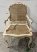 A Louis style cane back arm chair in a distressed white finish