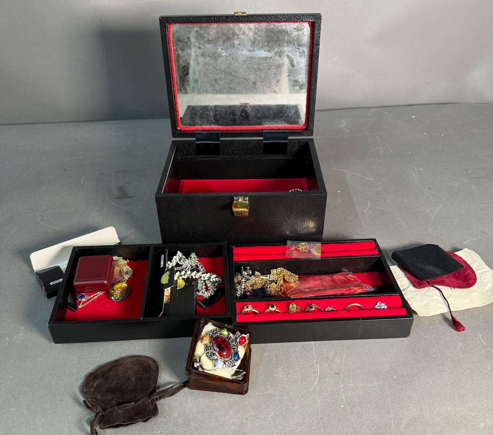 A selection of costume jewellery in a black jewellery box, a variety of styles and finishes to