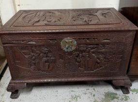 A Chinese camphor ornate trunk. Heavily carved with traditional scenes with hinged lid opening to