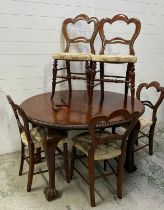 A circular mahogany extendable dining table on light paw feet and six medallion back chairs