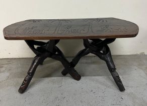 An African hardwood coffee table on interlocking legs and with a carved top featuring elephants