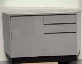 A contemporary grey laminate sideboard comprising of three graduated drawers flanked by a single